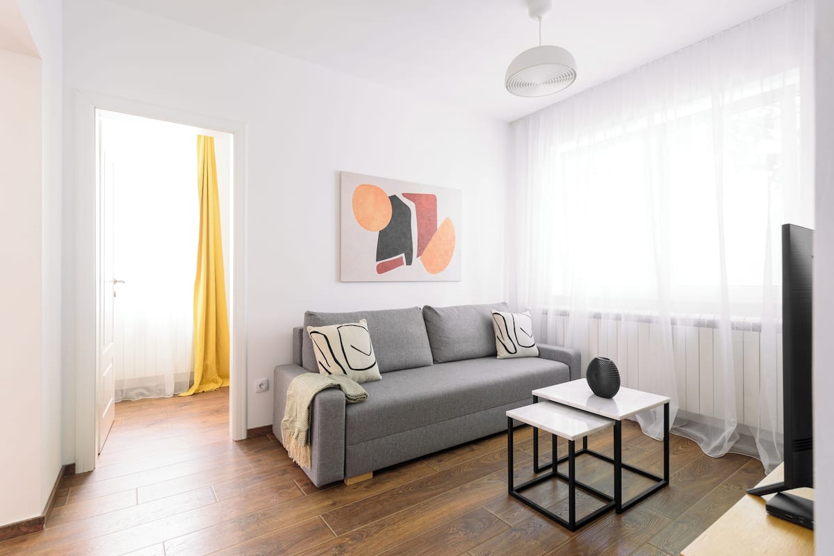 A modern living room with a grey sofa, a white coffee table, and a flat-screen TV.