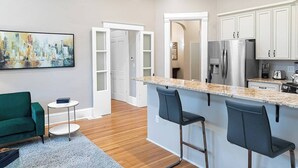 Una cocina moderna con encimera de mármol, electrodomésticos de acero inoxidable y una zona de bar con taburetes.