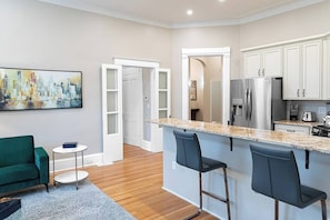 A modern kitchen with a marble countertop, stainless steel appliances, and a bar area with bar stools.