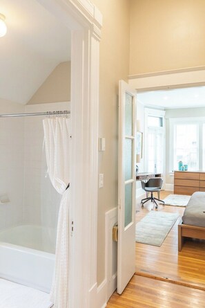 Une chambre avec une douche, un lit, une commode et une fenêtre.
