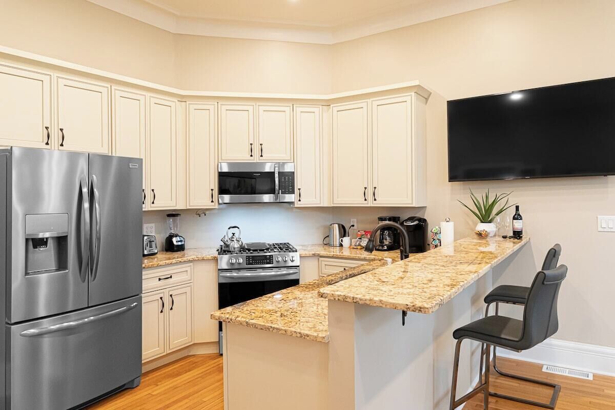 A modern kitchen with a built-in refrigerator, microwave, stove, and granite countertop island.