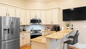 Una cocina moderna con refrigerador integrado, microondas, estufa y una isla de encimera de granito.