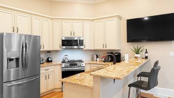 A modern kitchen with a built-in refrigerator, microwave, stove, and granite countertop island.