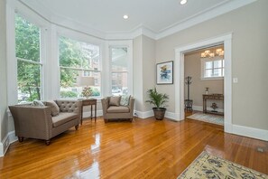 A spacious room with hardwood flooring, a large window, a sofa, a chair, and a potted plant. - 2 Bedrooms with 2 full baths unit (Cincinnati)