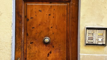 Une porte en bois, ornée d’une grille métallique et d’une plaque portant le numéro de l’adresse.