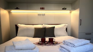 A neatly made bed with white linens, a tray with red mugs, and folded towels. - DEL RE FLORENCE HOME (Firenze)