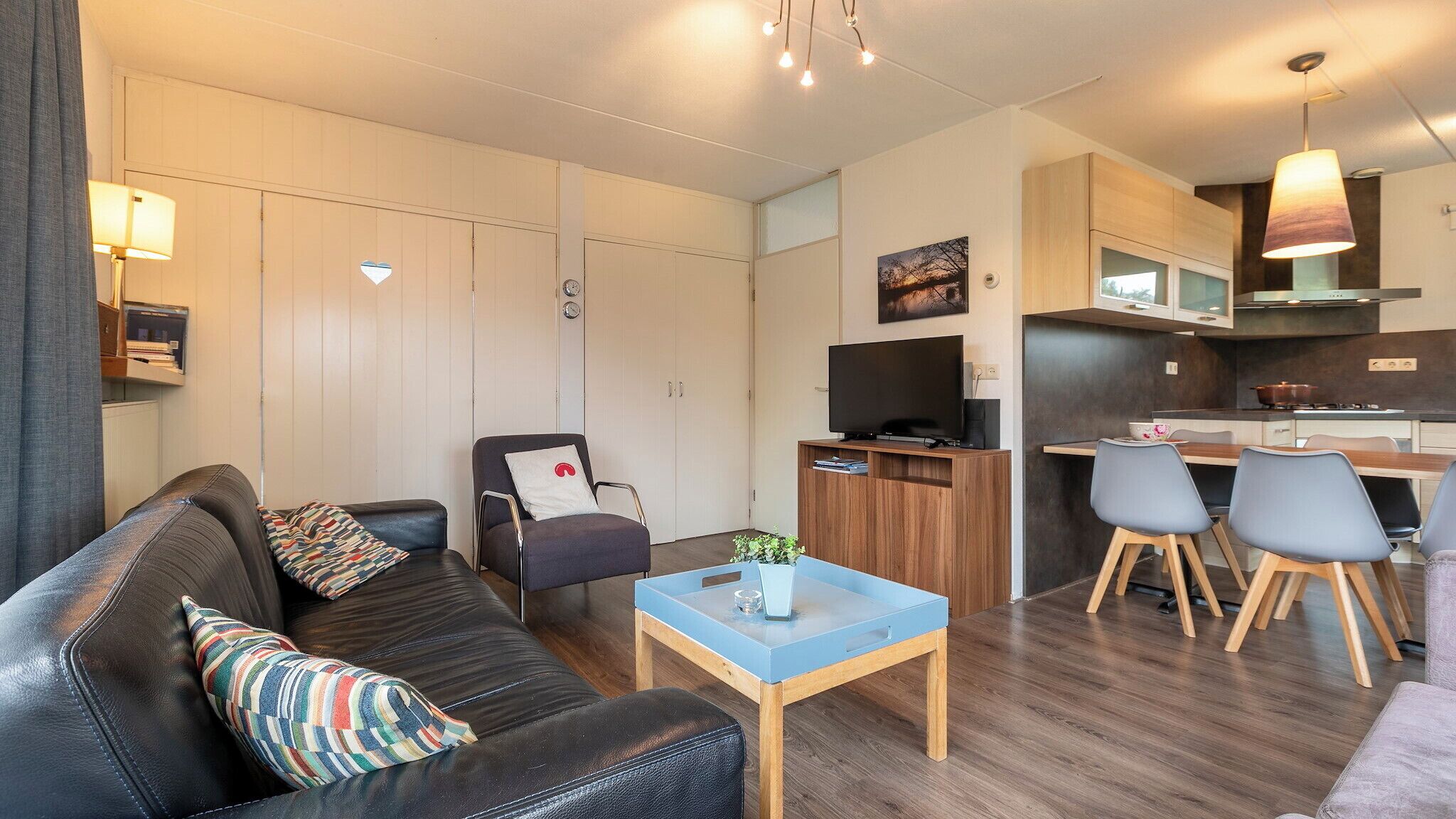 A modern apartment with a living room, a dining area, and a kitchenette.