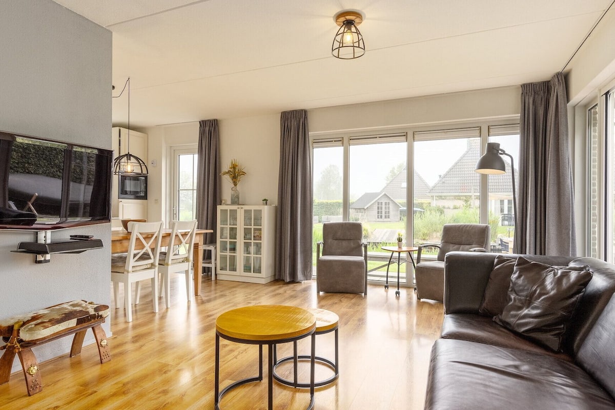 En moderne stue med en lædersofa, et træsofabord og et fjernsyn ophængt på væggen.