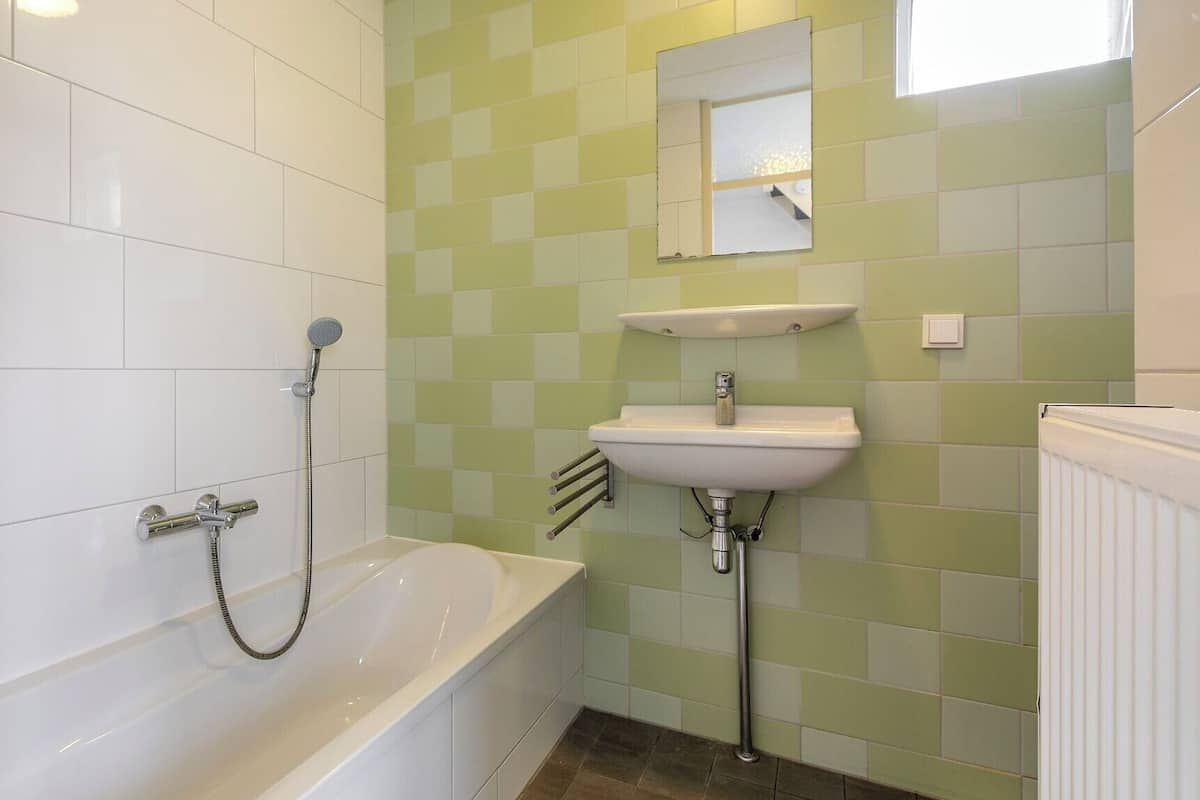 Et badeværelse med et hvidt badekar, en vask og et spejl.
