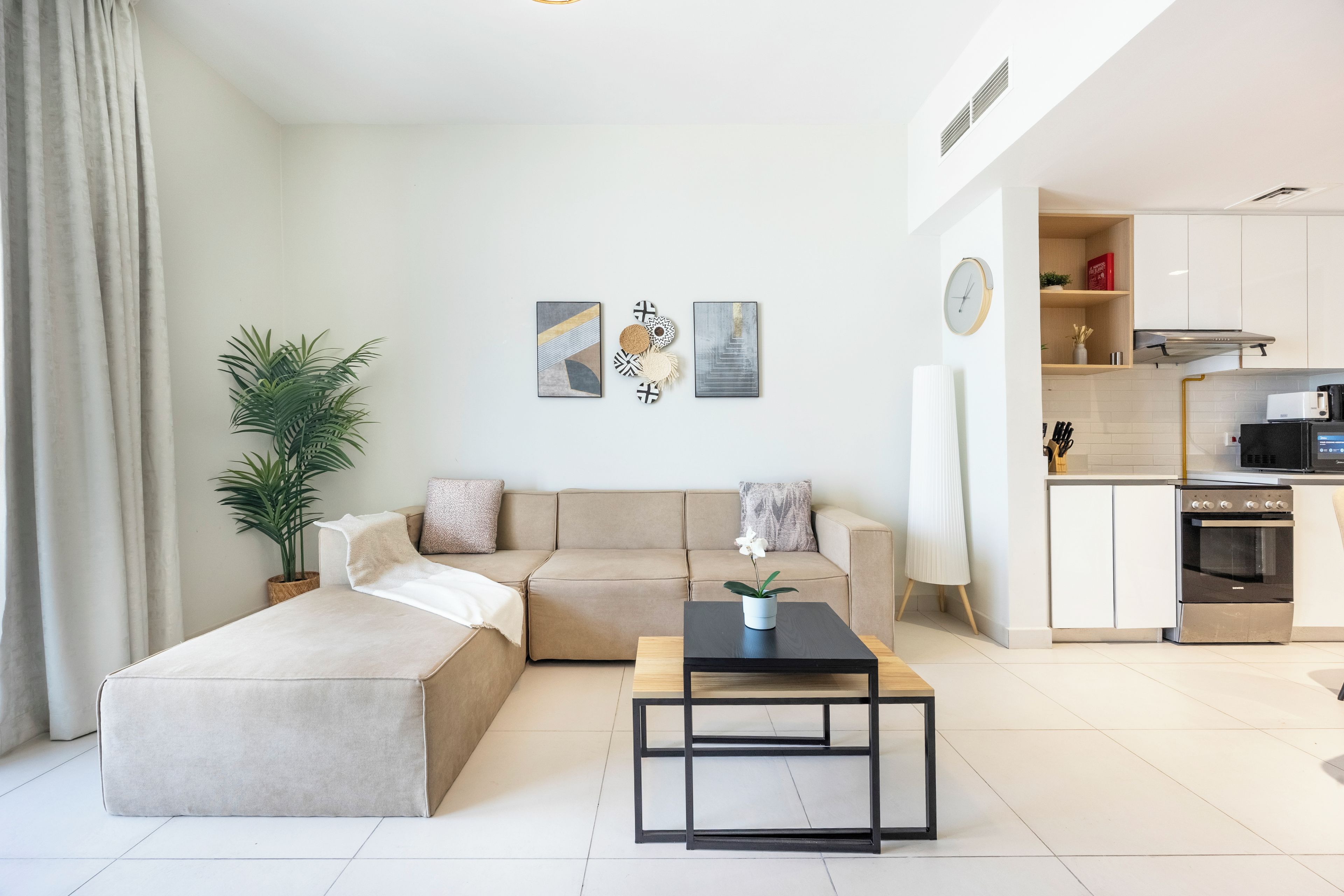 Un salon moderne avec un canapé d’angle, une table basse et une plante en pot.