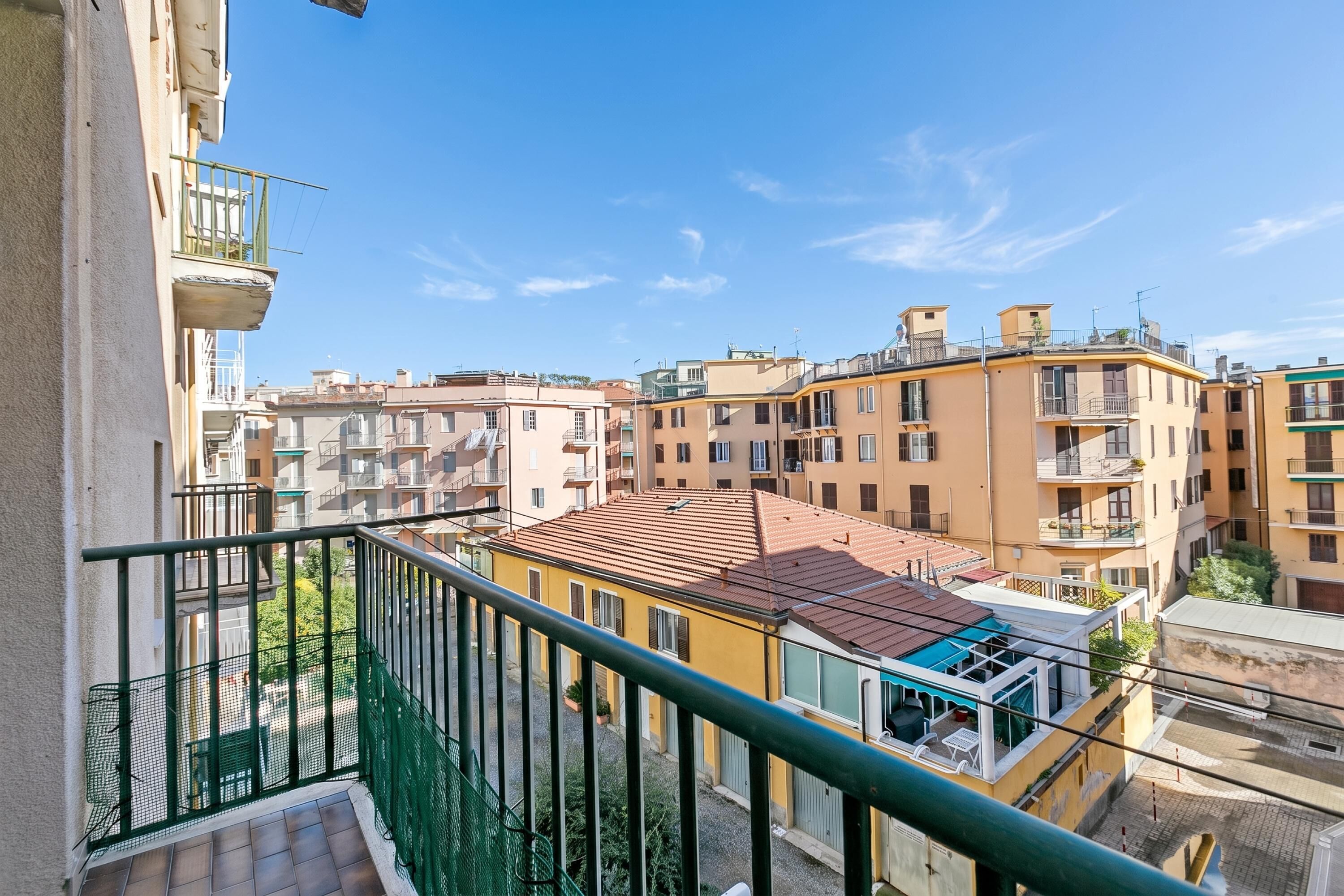 Zona residencial com edifícios altos, varandas e céu claro.
