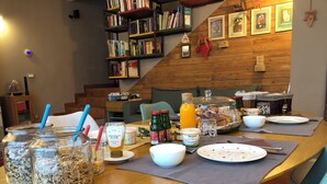 A dining table set with breakfast items, a bookshelf, and a staircase. - Melloni Street (Dolo)