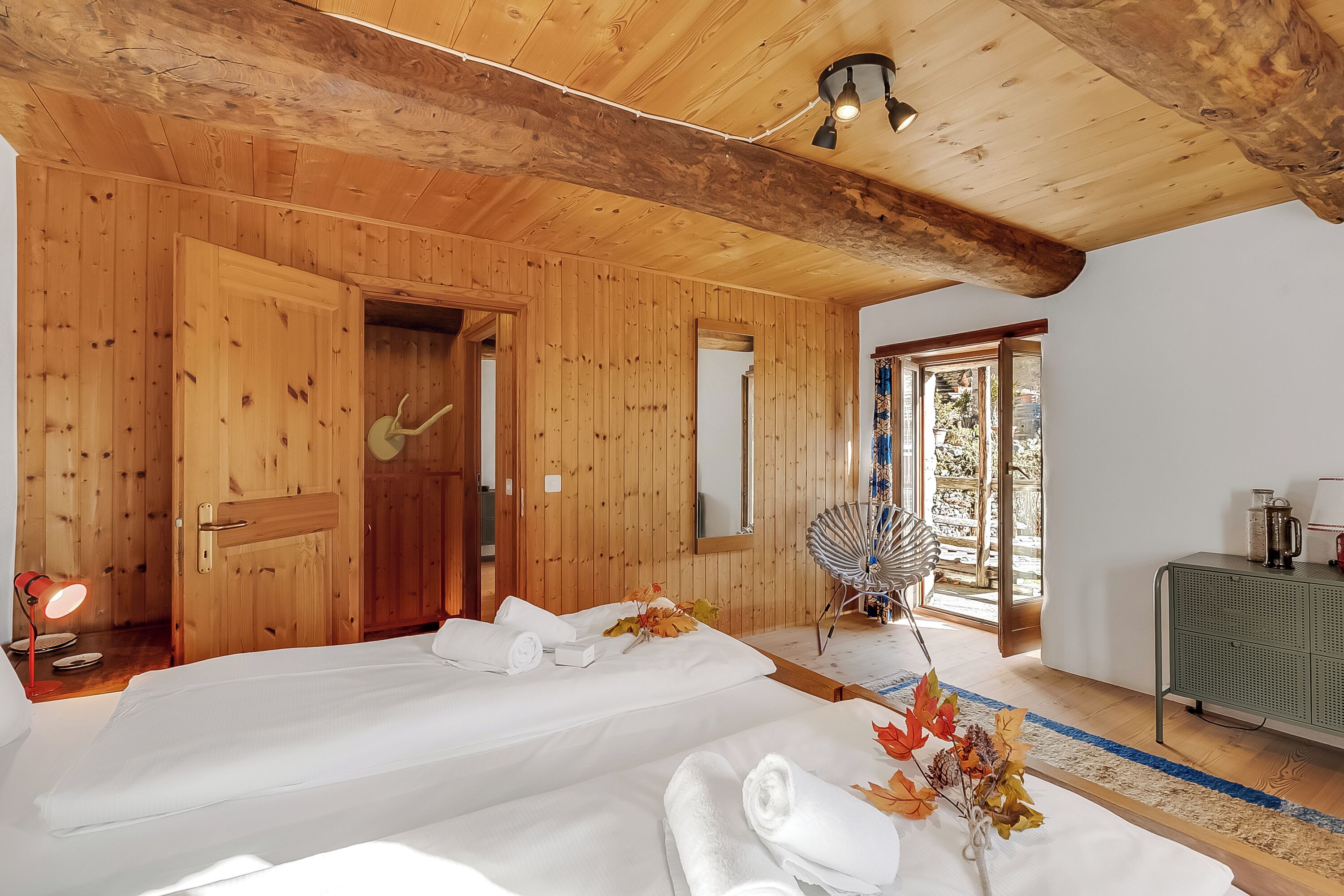 A wooden-paneled room with two beds, a mirror, a fan, and a green cabinet.