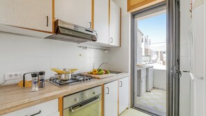 Una cocina moderna con estufa a gas, horno y vistas al balcón a través de la puerta abierta.