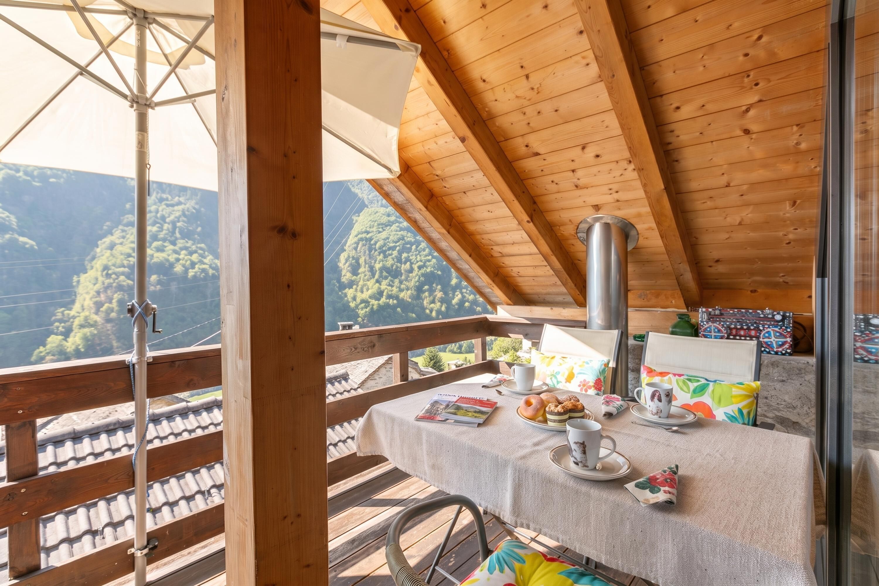 A wooden deck with a table set for breakfast, overlooking a mountainous landscape.