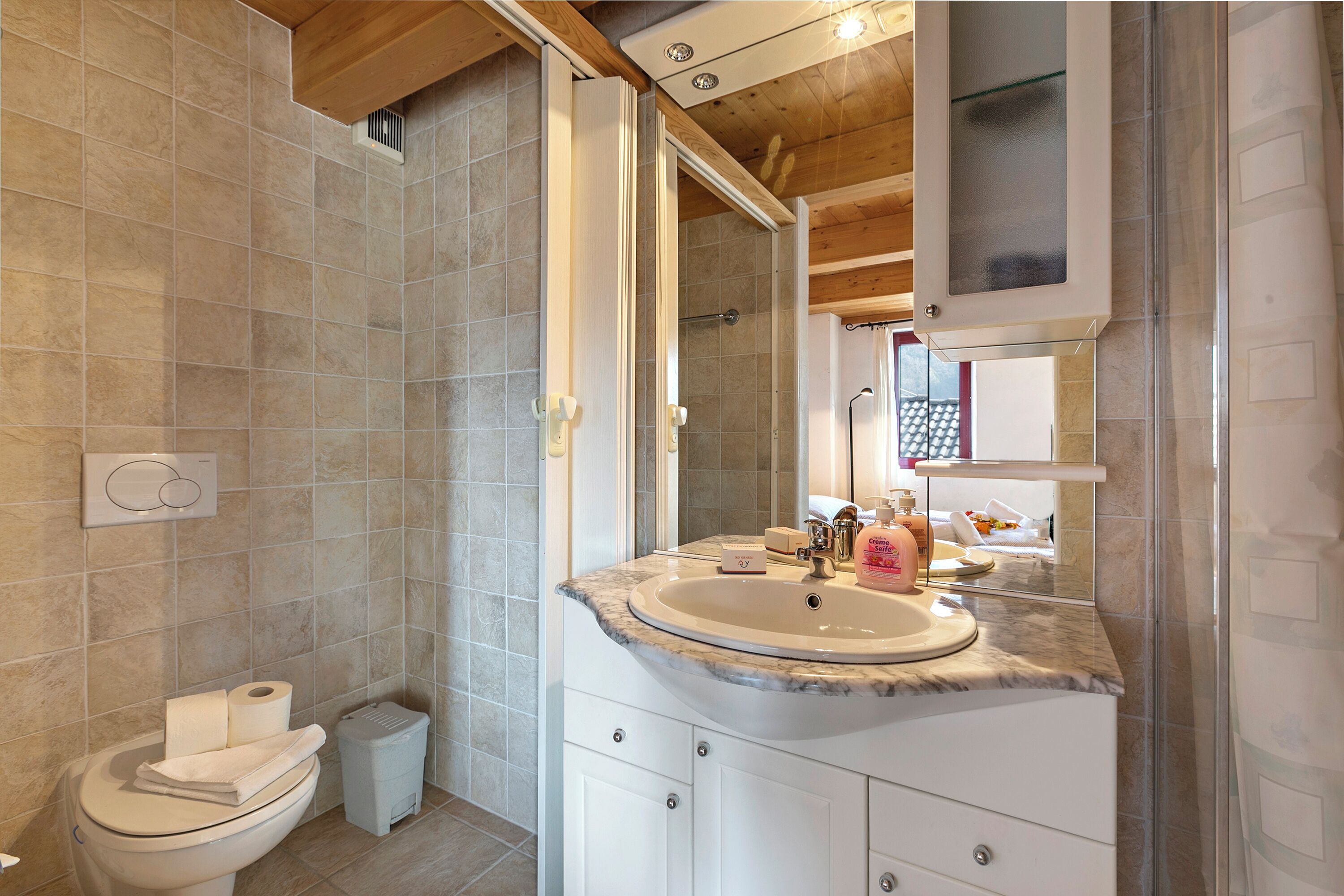 Een badkamer met een marmeren wastafel, toilet en douche.