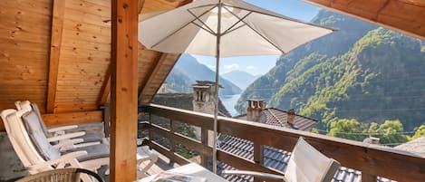 Un balcon en bois avec une table, des chaises et un parasol.