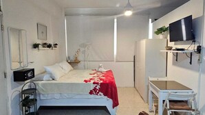 A bedroom with a bed, bedside table, and a TV mounted on the wall. - Apartamento Costa Azul en El Pueblito (Puerto Plata)