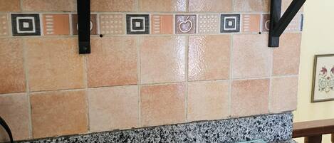 Una cocina con estufa a gas, repisas con frascos y una planta en maceta, además de un salpicadero decorativo.