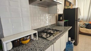 A kitchen with white cabinets, a granite countertop, a gas stove, and a water dispenser. - Apartamento Costa Azul en El Pueblito (Puerto Plata)