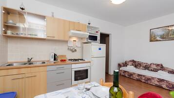 A compact kitchen with a gas stove, oven, microwave, and a dining area with a table set for two.