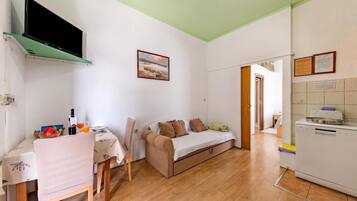 Un espacio habitable compacto con kitchenette, comedor y sofá.