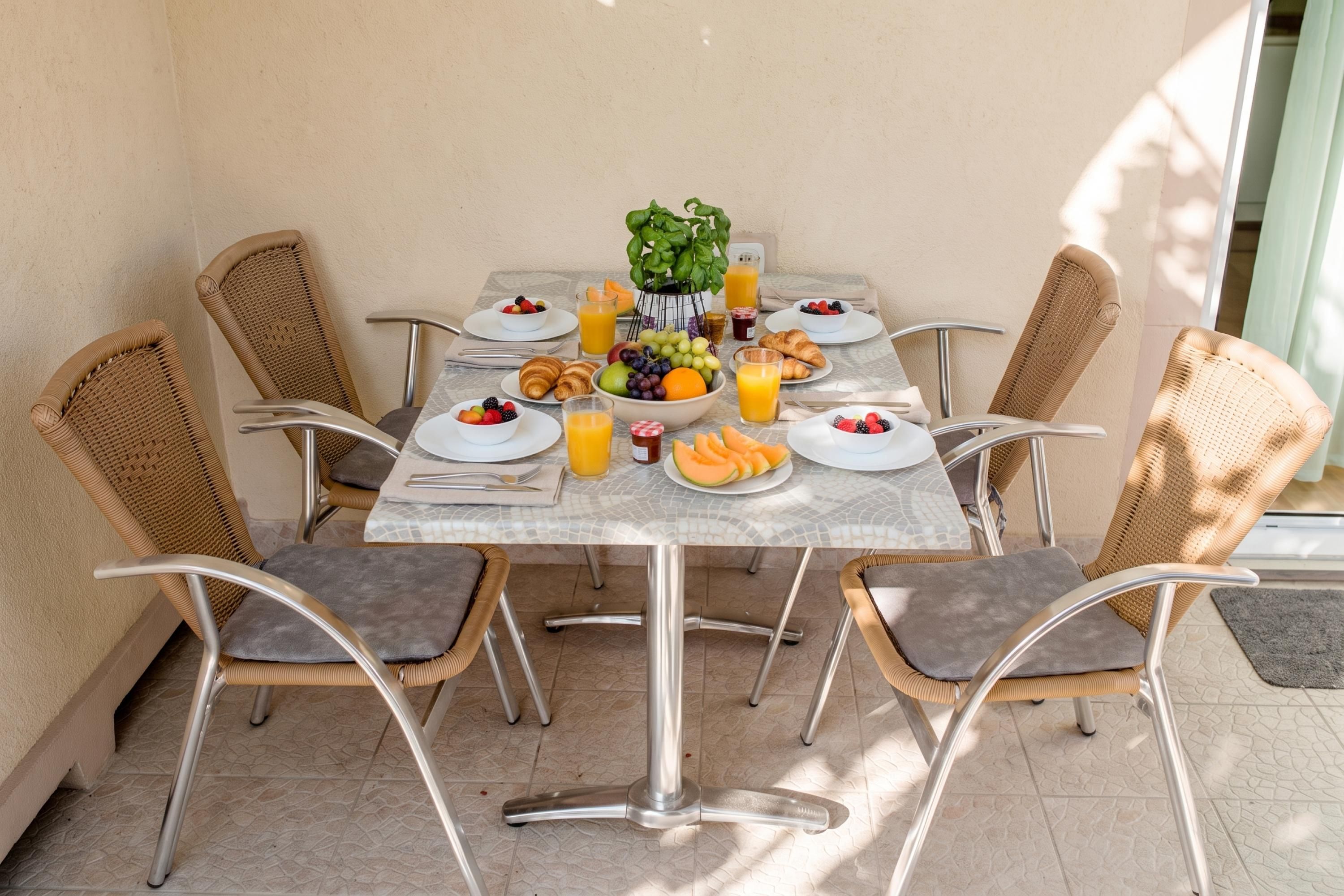 Una mesa de comedor con sillas, platos, tazones y vasos de jugo.