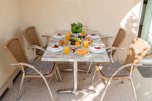 A dining table with chairs, plates, bowls, and glasses of juice. - Apartmani Mijatović (Lopar)