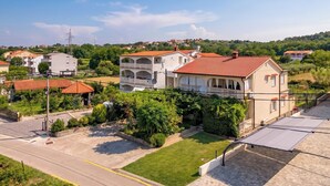 A residential area with houses, a clear sky, and a road. - Apartmani Mijatović (Lopar)