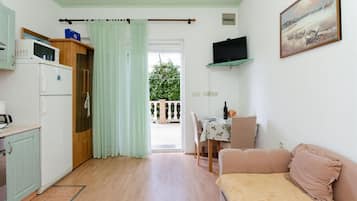 Un espacio habitable compacto con kitchenette, comedor y sofá.
