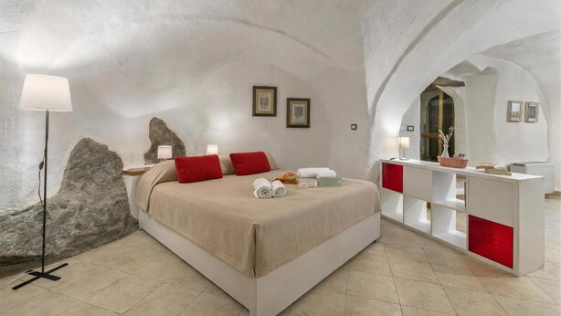 Een slaapkamer met een groot bed, een nachtkastje, een lamp en een spiegel.