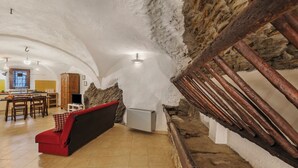 Een gezellig interieur met een stenen muur, een rode bank en een houten trap.