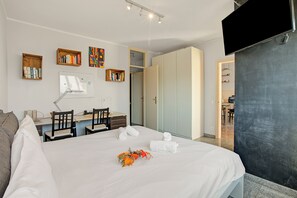 A hotel room with a bed, desk, chairs, and a TV. - Casa Tecitt With Shared Pool in Val Resa (Brione sopra Minusio)