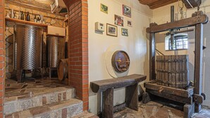 A rustic interior with stone steps, metal barrels, a wooden bench, and a wooden press. - Vineyard Cottage Brodaric (Metlika)