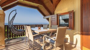 A terrace with wicker furniture, a dining table, and a view of the landscape. - Vineyard Cottage Brodaric (Metlika)