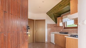 A kitchen with wooden cabinets, a white refrigerator, and a tiled backsplash. - Vineyard Cottage Brodaric (Metlika)