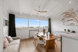 A modern kitchen with a dining area, large windows, and a ceiling fan. - Sky View Apartment Monopoli (Monopoli)