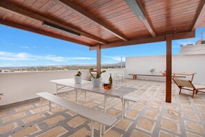 A covered outdoor patio with a table and chairs, a bench, and potted plants. - Sky View Apartment Monopoli (Monopoli)