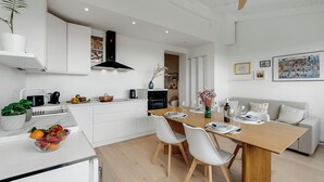 A modern kitchen with white cabinets, a wooden dining table, and a ceiling fan. - Sky View Apartment Monopoli (Monopoli)