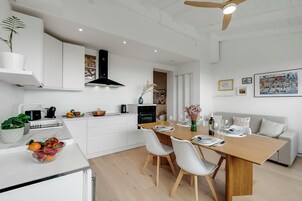 Una cucina moderna con mobili bianchi, un tavolo da pranzo in legno e una ventola a soffitto.