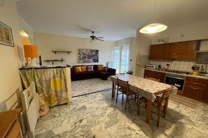 A compact living space with a dining area, kitchen, and a sofa in the living room.
