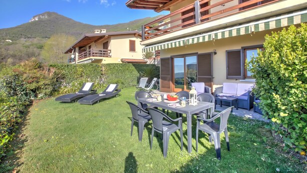 A two-story building with a balcony, a dining area with outdoor furniture, and a view of a mountain. - Lakeview Bliss / Pool & Fenced Garden (Villanuova sul Clisi)
