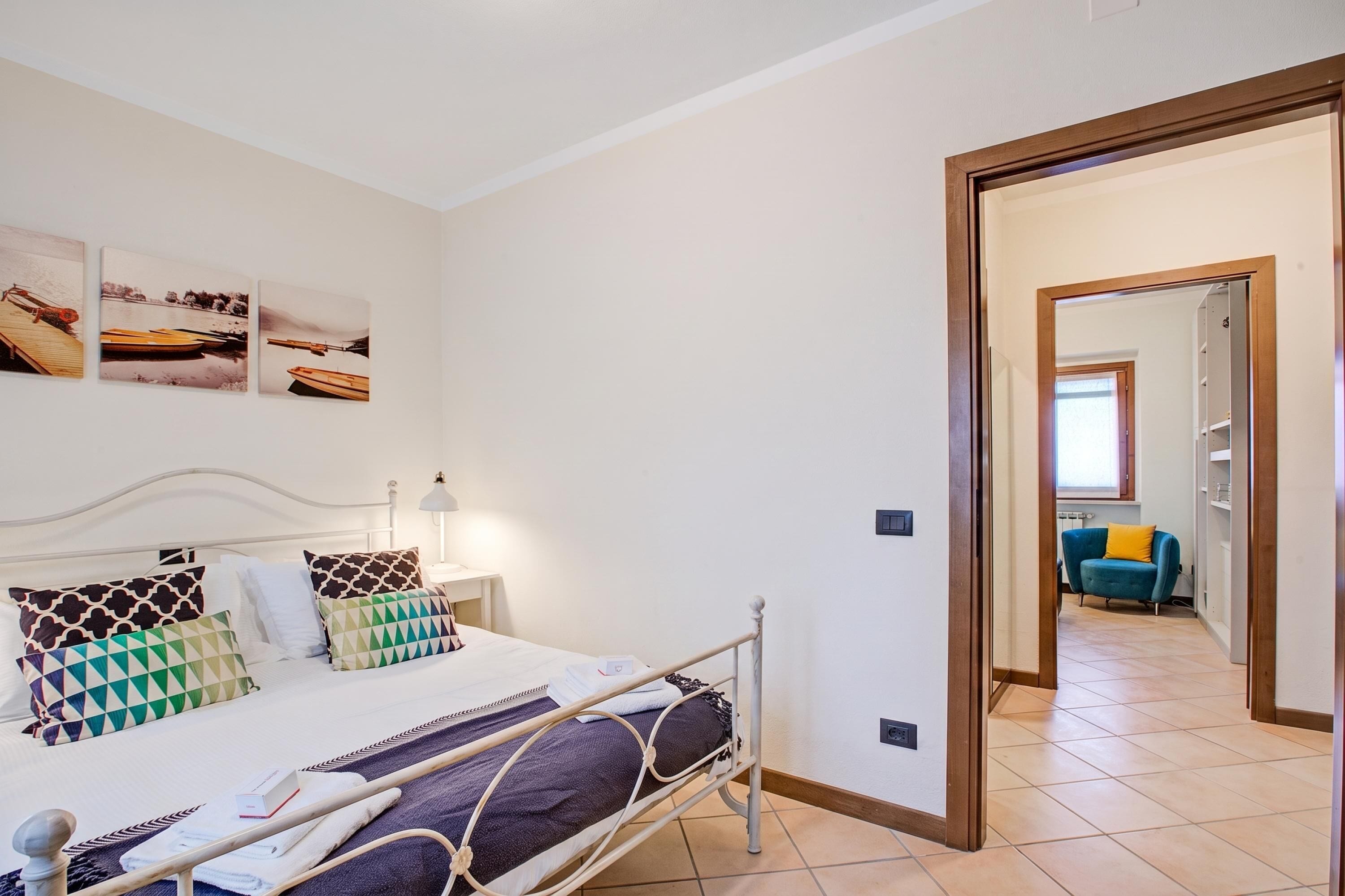 Une chambre à coucher avec un lit, des oreillers, une table de chevet et un tableau accroché au mur.