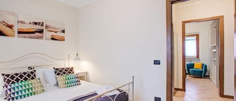 A bedroom with a bed, pillows, a bedside table, and a wall-mounted picture.