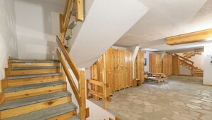 A staircase with wooden steps and a handrail, leading to a room with wooden cabinets and a stone-patterned floor. - Appartamento Quota 1800 for 4 + Garage + ski Storage (Claviere)