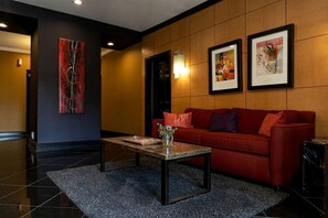 Un moderno vestíbulo de hotel con un sofá rojo, una mesa de centro y dos obras de arte enmarcadas en la pared.