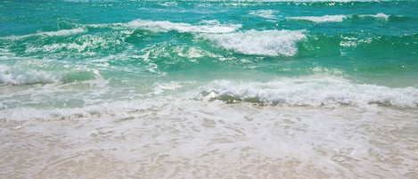 A beach with waves and clear water.