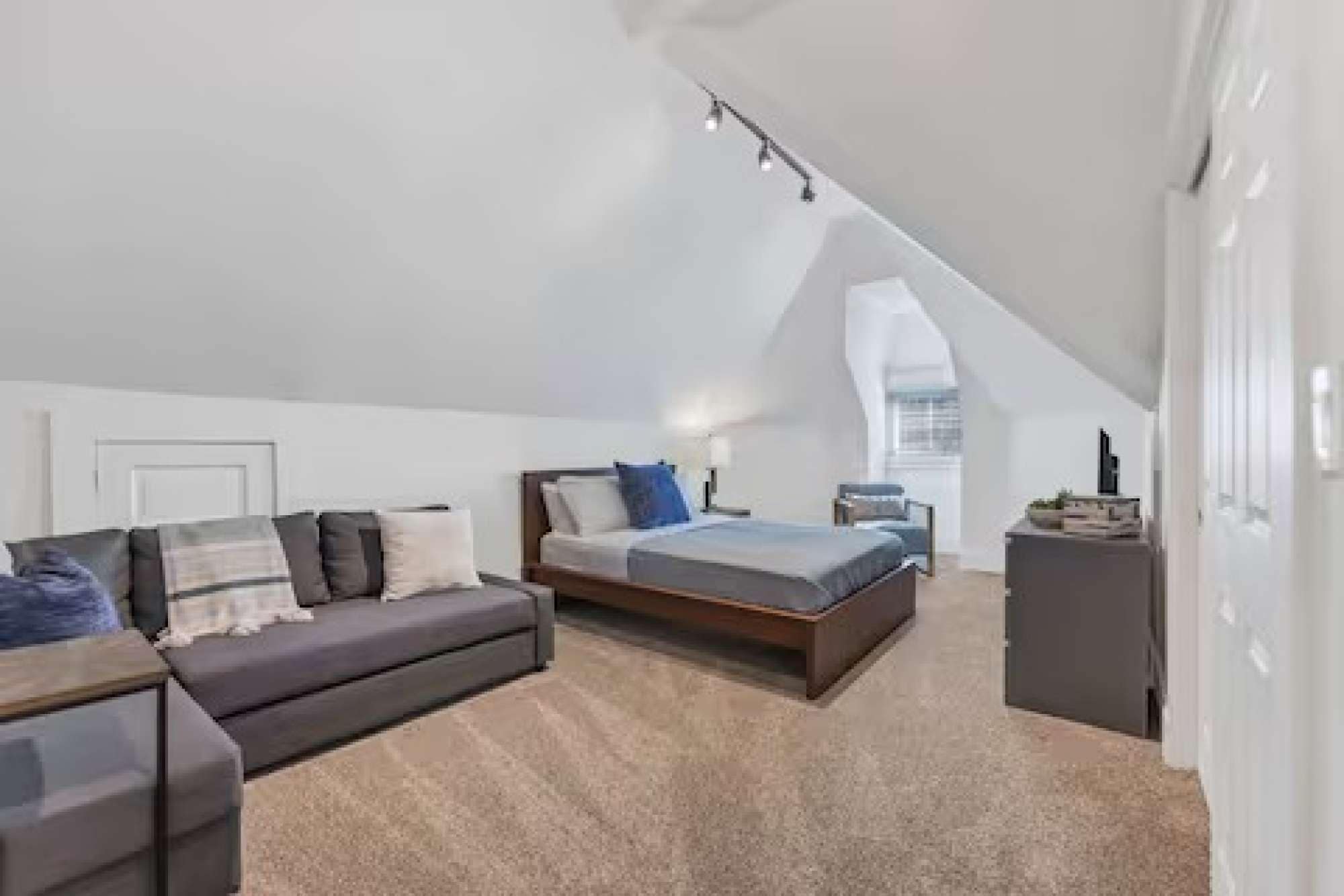 Een moderne loft slaapkamer met een hoogslaper, een bank en een bureau.