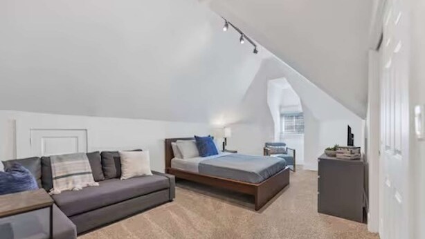 Ein modernes Schlafzimmer im Loftsstil mit Hochbett, Sofa und Schreibtisch.