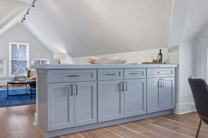 A modern kitchen with a large island, built-in cabinets, and a view of the living area.
